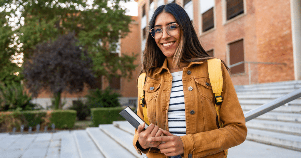 High school student smiling on a college campus visit, feeling hopeful about their future